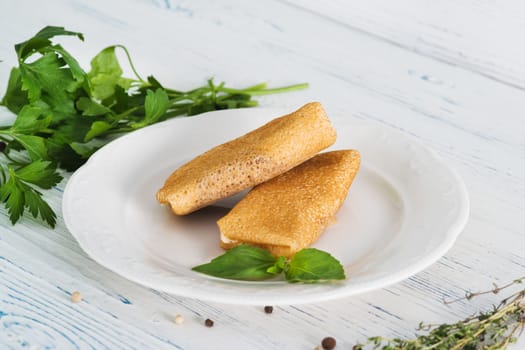 Stuffed pancakes on light wooden background