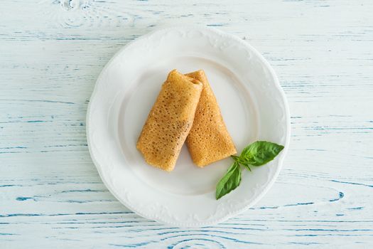 Stuffed pancakes on light wooden background