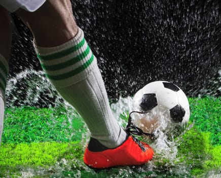 soccer football players kicking to soccer ball on green grass field with splashing of transparent water against black background