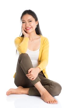 Full length Asian female sitting on floor smiling and looking at camera, isolated on white background.