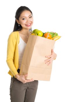 Happy smiling young pan Asian woman holding paper shopping bag full of groceries isolated on white background.