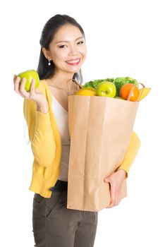 Happy young Asian female shopper, hands holding shopping bags filled with groceries and smiling, isolated standing on white background.