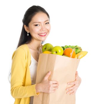Happy young Asian woman shopper, hands holding shopping bags full of groceries and smiling, isolated standing on white background.