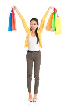 Happy young Asian woman shopper, hands outstretched holding shopping bags and smiling, full length isolated standing on white background.