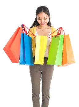 Happy young Asian woman shopper, hands holding shopping bags and smiling, isolated standing on white background.