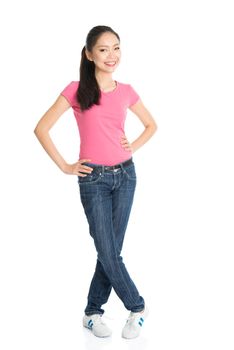 Portrait of young Asian female in pink shirt and jeans with ponytail hair is smiling, full length standing isolated on white background.