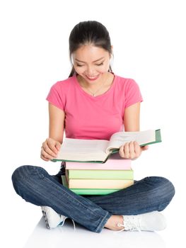 Full body young Asian collage female teen student in pink shirt reading textbooks, seated on floor, full length isolated on white background.