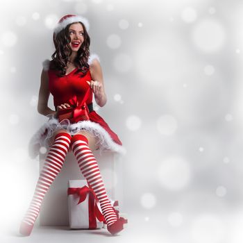 Beautiful pin-up Christmas woman in Santa Claus costume unpack gift