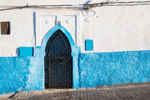 White house with a bright blue detail and a lining of the entrance door. Coast city Sidi Ifni, Morocco.