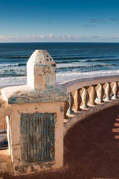 Old fence enlightened by an evening sunlight. View on the Atlantic Ocean. Sky with little clouds. Sidi Ifni, Morocco.