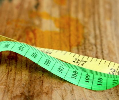 picture of a yellow and green tape measure on wood background