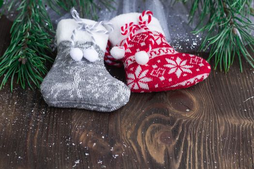 Christmas composition of two knitted socks and xmas tree branches on wooden background