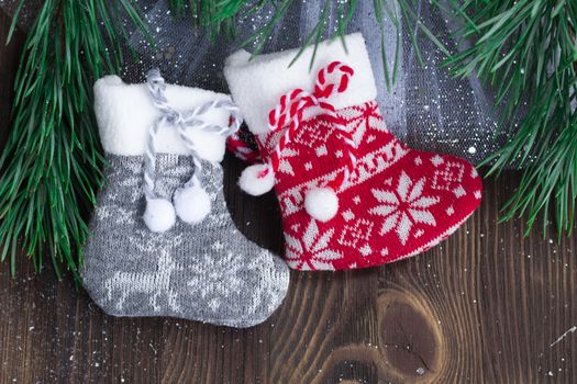 Christmas composition of two knitted socks and xmas tree branches on wooden background