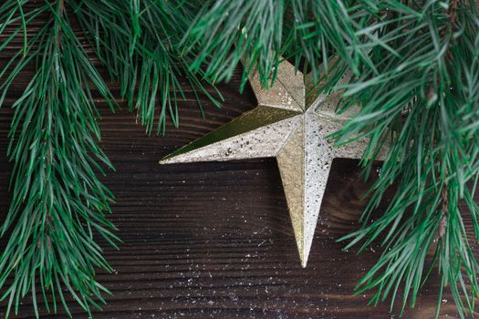 Christmas composition of golden star ornament and xmas tree branches on wooden background
