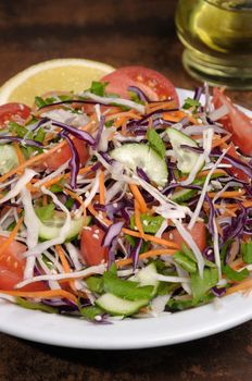 Salad of white and blue chopped cabbage, carrots, cucumber, tomato dressed with oil, lemon, sesame
