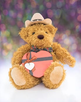 Teddy bear with 
Red heart shaped gift box on bokeh background