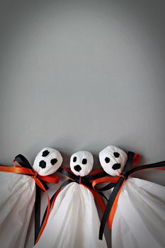 Halloween concept background : Three halloween ghosts DIY made from white tissue paper, black and orange ribbon on gray background