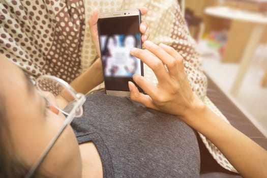 Woman holding and using smartphone at room.