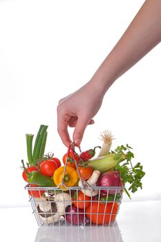 Hand with wire shopping basket full of fresh vegetables