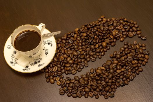 A cup of coffee and coffee beans like one big bean on the table.
