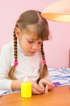 The girl sticks a small bow of colored paper