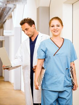 Photo of a nurse and doctor with medical charts in the hallway of a hospital.