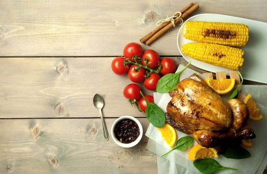 Roast turkey with corn and vegetables on top of a wooden table with space 