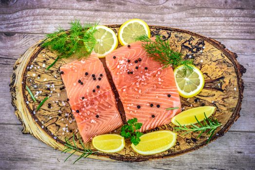 Overhead shot on fresh Salmon steak on wooden birch stump pickled lemon, pepper, sea salt, rosemary, parsley, dill