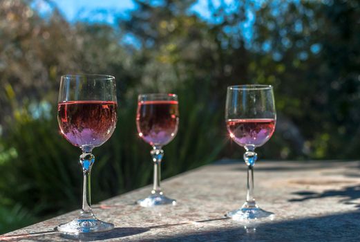 Rosè wine in stemmed glasses on a table in a garden in a sunny day