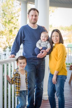 Young Mixed Race Chinese and Caucasian Family Portrait On Their Front Porch.