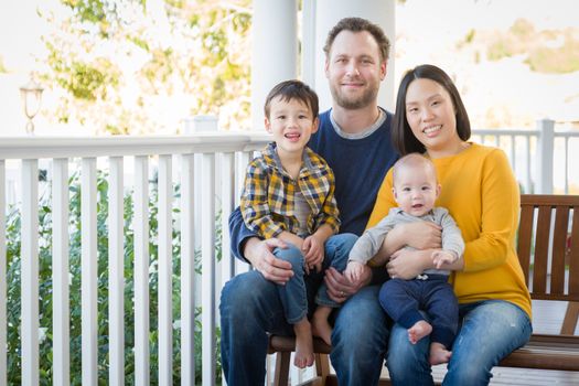 Young Mixed Race Chinese and Caucasian Family Portrait On Their Front Porch.