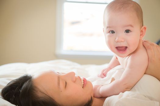 Young Mixed Race Chinese and Caucasian Baby Boy Laying In His Bed with His Mother.