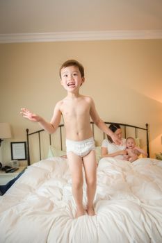 Young Mixed Race Chinese and Caucasian Boy Jumping In Bed with His Family.