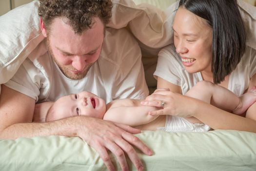 Mixed Race Chinese and Caucasian Baby Boy Laying In Bed with His Father and Mother.