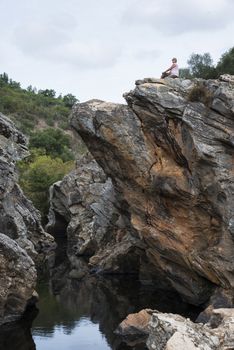 woman sitting on the high rocks of pego des pias in portugal alentejo area