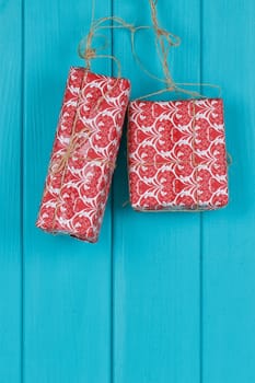 Christmas background of red apresents Christmas decorations hanging on rope in front of blue wooden background.