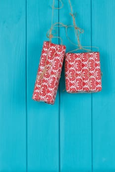 Christmas background of red apresents Christmas decorations hanging on rope in front of blue wooden background.
