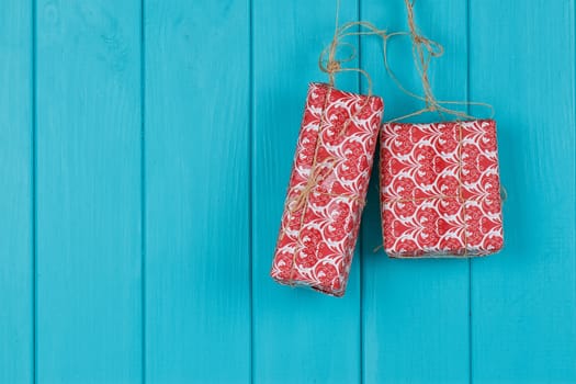 Christmas background of red apresents Christmas decorations hanging on rope in front of blue wooden background.