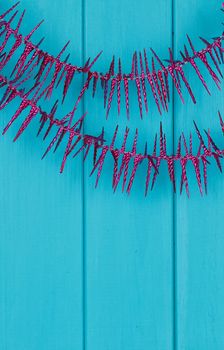 Purple Christmas tree garland on blue wooden background