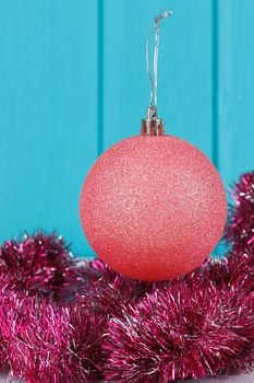 Pink Christmas ball and Christmas garland on blue wooden background