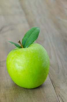 Ripe green apple with leaf  on a wooden background