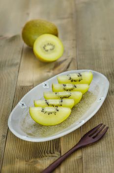 golden kiwi fruit and sliced on dish over wooden background