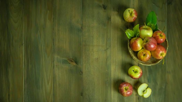 Top view red and yellow apple with leaves and  bamboo basket on wooden background with free space for text