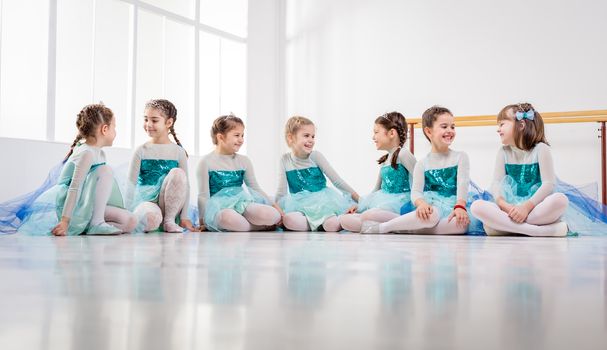 Group of a little girls in dresses taking a break from ballet class.