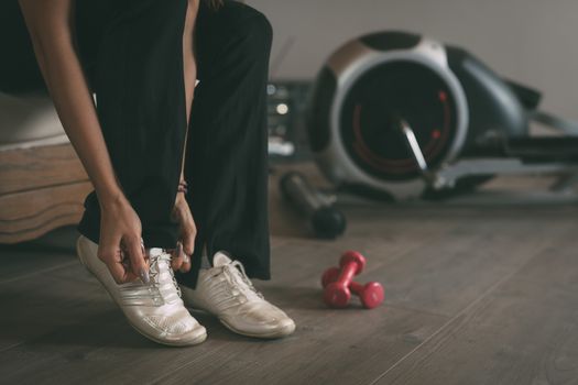 Female hand tying shoelace on sneakers. Close up.