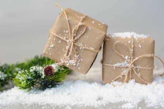 gift boxes and spruce twigs in snow. Christmas decor