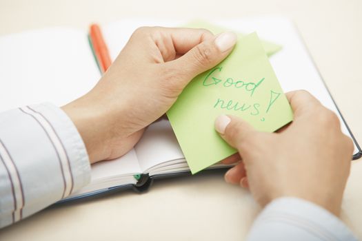 Woman holding sticky note with Good news text