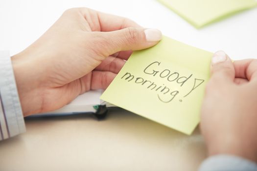 Hands holding sticky note with Good morning text