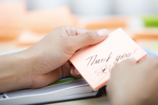 Human hand holding adhesive note with Thank you text