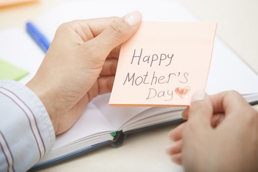 Hands holding sticky note with Happy mothers day text